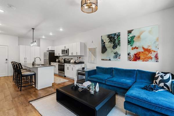 Open living room with blue velvet sectional and kitchen island at The Revival Apartments, Utah, 84101